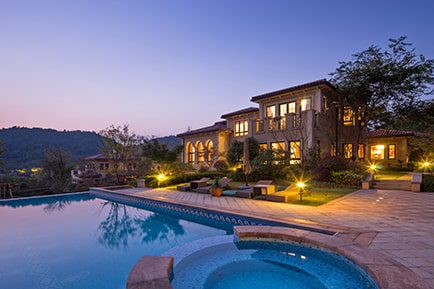 A beautiful image of house with lights on taken in the evening and swimming pool on the side of the house